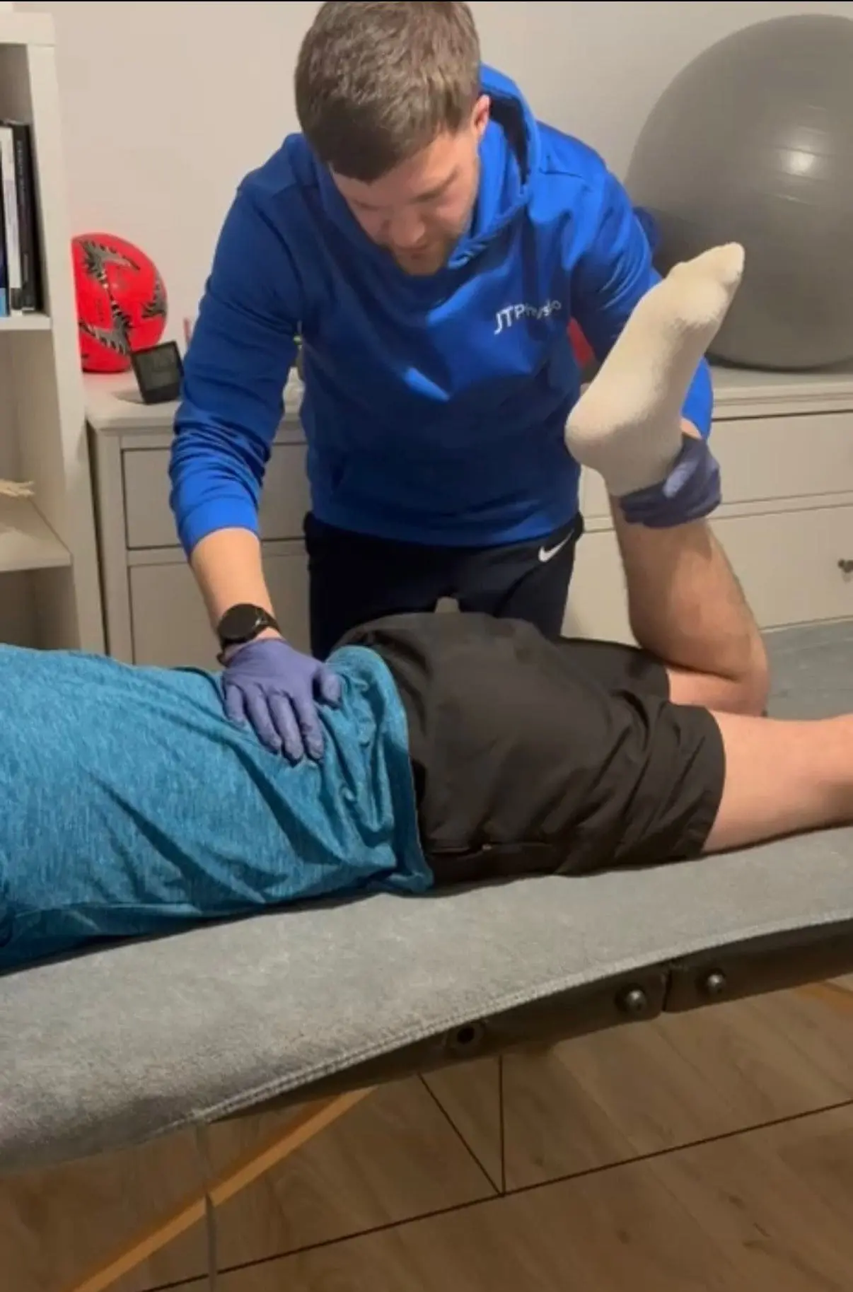 Football injury physiotherapy assessment in Kilmarnock, Ayrshire with client performing movement analysis while physiotherapist observes and takes notes
